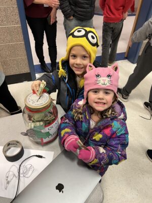 Boy and girl putting money into jar for KSL Quarters for Christmas