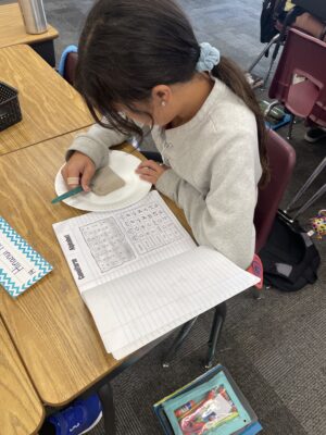 Student carves cuneiform writing into clay tablet.